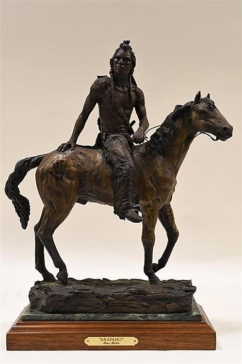 A bronze or wood carving of a native American seated on a horse.